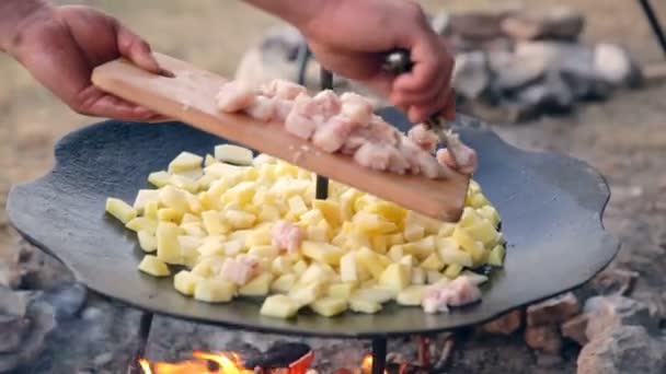 De man zet de vlees en vet in een koekenpan. Aardappel en vlees op ploeg schijf fornuis. Aardappelen en vlees op schijf grill. — Stockvideo