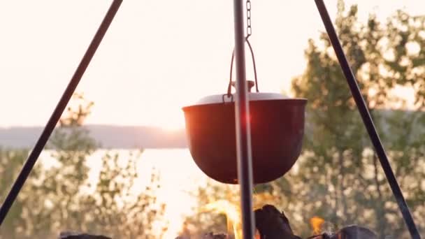 DOLLY MOTION: Cozinhar no fogo ao nascer do sol. Chá em chamas. Panela turística no fogo . — Vídeo de Stock