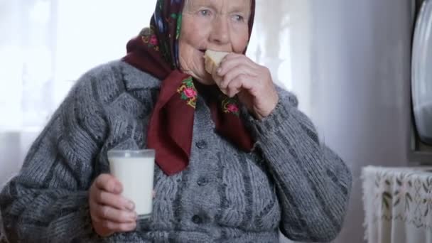 Senior vrouw drinken van een glas melk en wit brood — Stockvideo