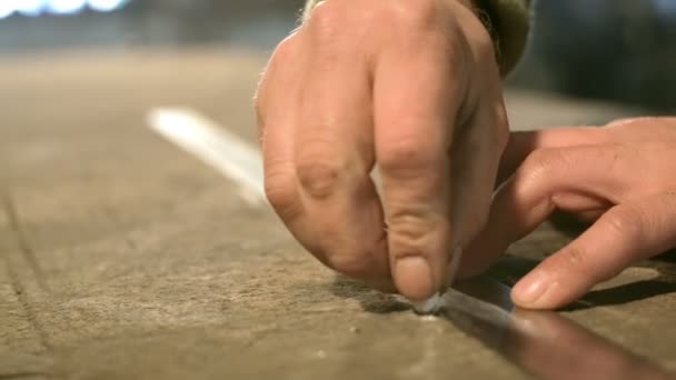Nahaufnahme eines jungen Schmieds, der mit einem Metalllineal einen Kreidestrich auf den Tisch zeichnet. — Stockvideo