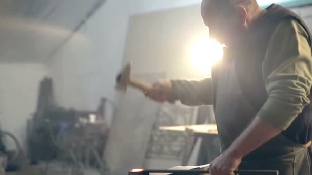 Силует втомленого молодого коваля фартух утворює гарячий метал з молотком — стокове відео