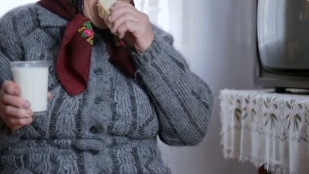 Senior woman drinking a glass of milk and white bread — Stock Video