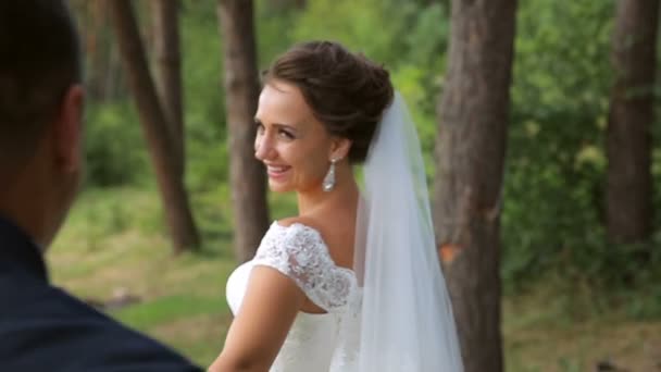 Los recién casados felices van de la mano. La novia mira a su alrededor y sonríe a su prometido — Vídeos de Stock