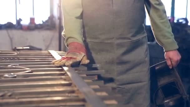 Un joven herrero de cerca con guantes toca productos metálicos — Vídeo de stock