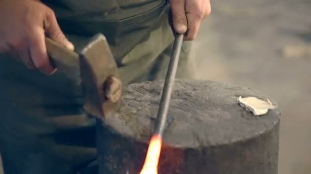 Blacksmith bend hot metal with a hammer on the anvil in the smithy — Stock Video