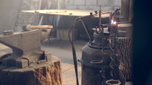 Tired young blacksmith apron in shaping hot metal with hammer — Stock Video