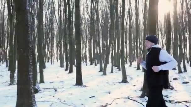 Paseo de invierno - un joven caminando por el parque, escuchando música con auriculares. Alrededor de mucha nieve — Vídeos de Stock