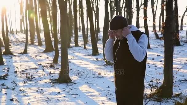 Sport man met hoofdtelefoon in het park bij zonsondergang. Winter joggen in het park. Donker — Stockvideo