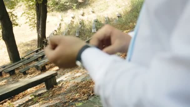 Zakenman op een bankje in het park met polshorloge — Stockvideo