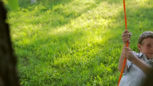 Le gars du village monte une balançoire du pneu, magnifiquement peint dans le jardin. Mouvement lent — Video