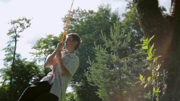 Gelukkige jongen swingen op de banden van een auto. Zomervakantie — Stockvideo