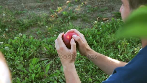 Een man probeert te verdelen de rode appel — Stockvideo