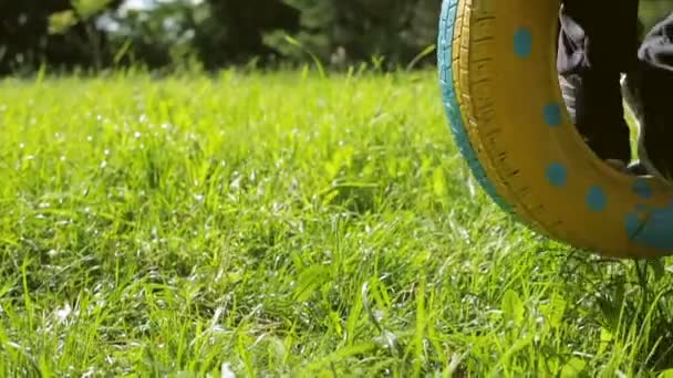 The boy swings on the wheel at midday — Stock Video