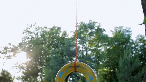 Swing de la rueda en el jardín. Reutilización de la rueda pintada en color azul-amarillo — Vídeo de stock