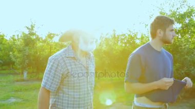 Torunu onun dedesi ile bir elma taşıyor. Orchard için yürüyüş