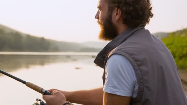 Un tipo con spinning remolque pescado desde el río — Vídeos de Stock