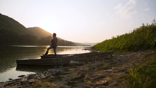 Mann fängt Fische bei Sonnenuntergang. Holzboote werden an der Bure festgemacht — Stockvideo