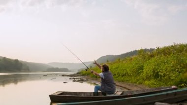 Genç bir balıkçı yakalar bir balık bir tekne bir nehir üzerinde günbatımında