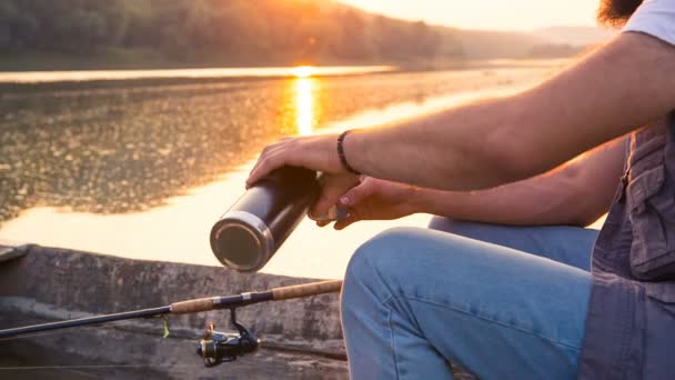 Un pescador vierte un café sentado en un bote de madera — Vídeo de stock