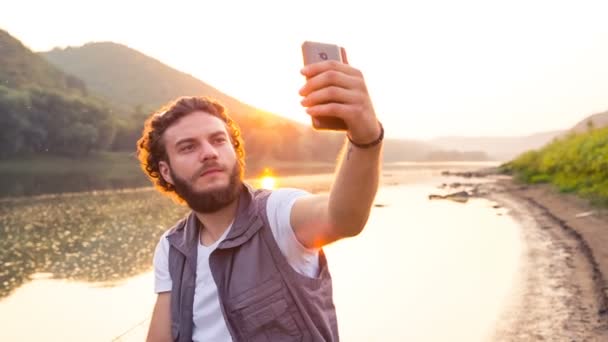 Un pescador hace un selfie en la puesta del sol en una tarde de verano. Hace una foto de su descanso — Vídeo de stock