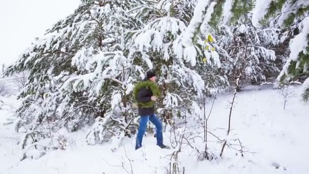 Um homem vai com uma grinalda de Natal numa floresta gelada de neve. Preparação para férias de inverno. Tradições de feriados de Ano Novo — Vídeo de Stock