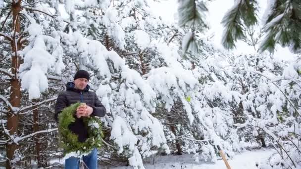 Een man maakt Christmas decor op de deur met zijn eigen handen in het bos. — Stockvideo