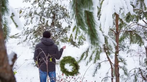 Homem e decoração de Natal em uma porta em uma floresta nevada — Vídeo de Stock