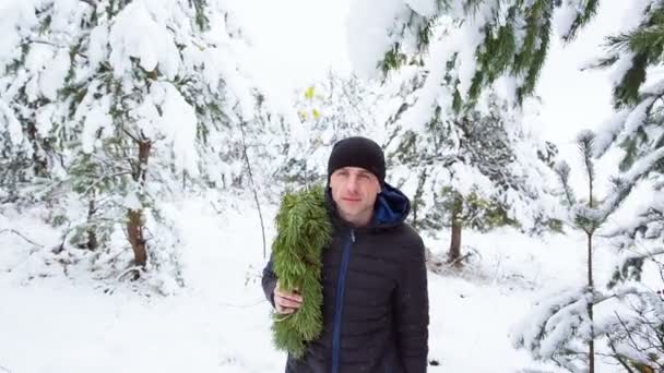 Ο τύπος με ένα στεφάνι Χριστουγέννων στο δάσος — Αρχείο Βίντεο