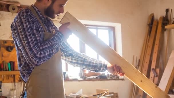 Der bärtige Tischler prüft das hölzerne Werkstück — Stockvideo