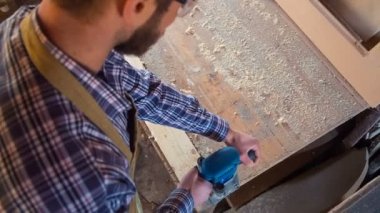 Marangoz bir öğütme aracı ile çalışır. Ağaç işleme işlemi yükseklikten