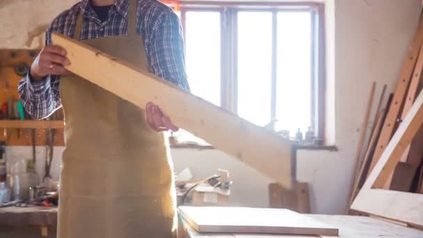 El joven carpintero inspecciona los tableros de la tienda — Vídeo de stock