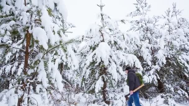 Ένας άνθρωπος που πηγαίνει με ένα Χριστουγεννιάτικο στεφάνι φτιαγμένο από τα χέρια του στο δάσος — Αρχείο Βίντεο