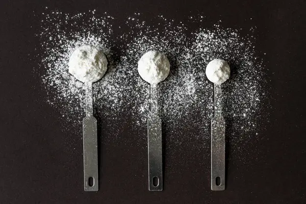 spoonfuls of flour lie on a table.