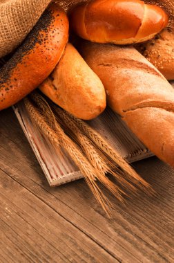 Ekmek, baget, somun ve ahşap masa üzerine buns. Dikey