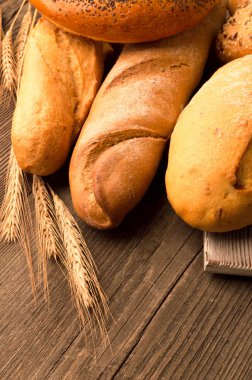 Ekmek, baget, somun ve ahşap masa üzerine buns. Dikey