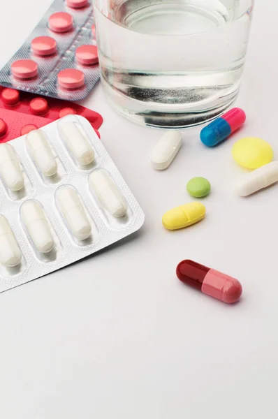 Лекарства. Цветные таблетки со стаканом воды — стоковое фото