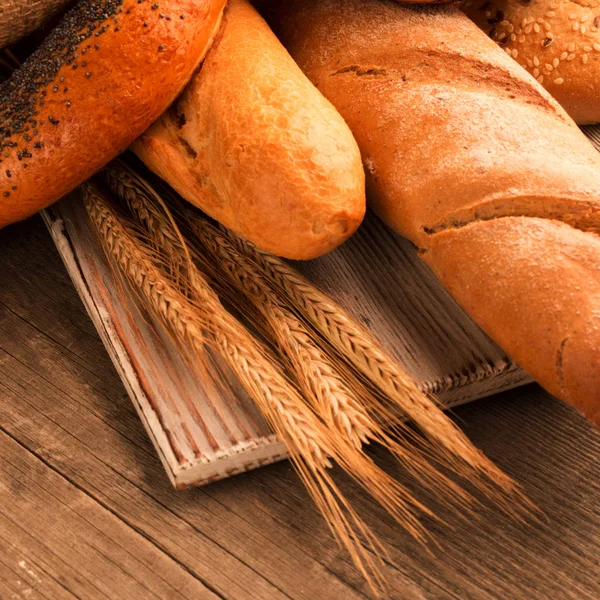 Ekmek, baget, somun ve ahşap masa üzerine buns. Kare