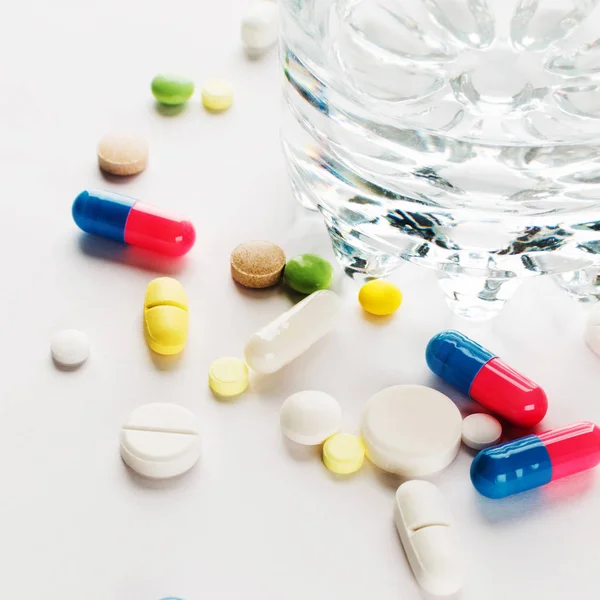 Медицина. Кольорові таблетки зі склянкою води. площі — стокове фото