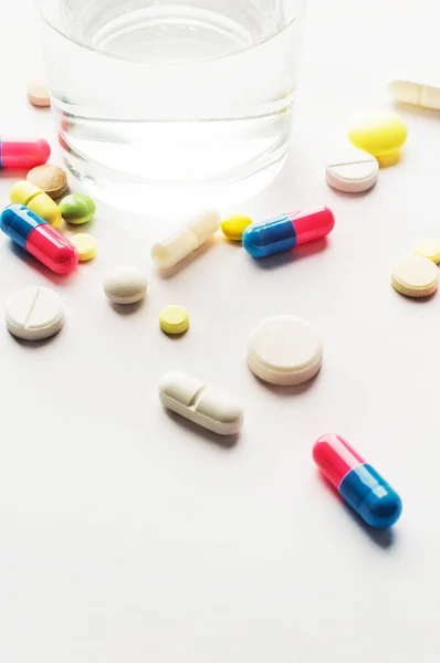 Лекарства. Цветные таблетки со стаканом воды — стоковое фото