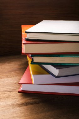 Tahta masanın üzerinde bir yığın kitap var.