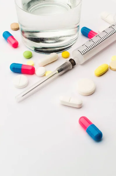 Лекарства. Цветные таблетки и шприц со стаканом воды — стоковое фото