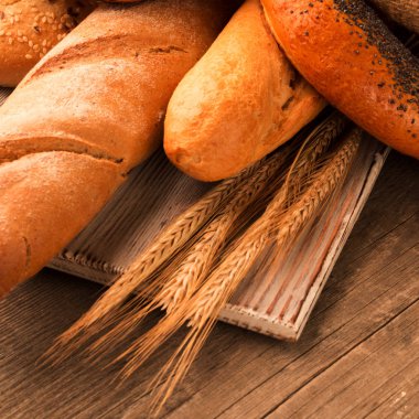 Ekmek, baget, somun ve ahşap masa üzerine buns. Kare