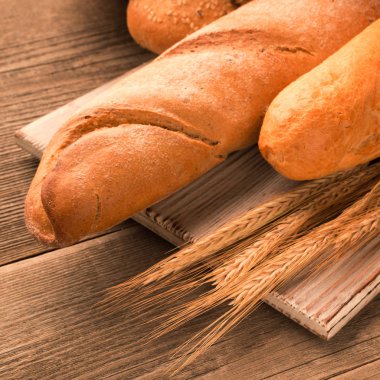 Ekmek, baget, somun ve ahşap masa üzerine buns. Kare