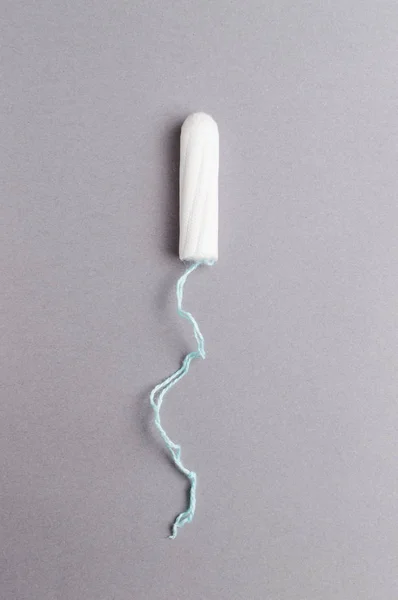 Менструальный тампон на сером фоне. Время менструации. Гигиена и защита — стоковое фото