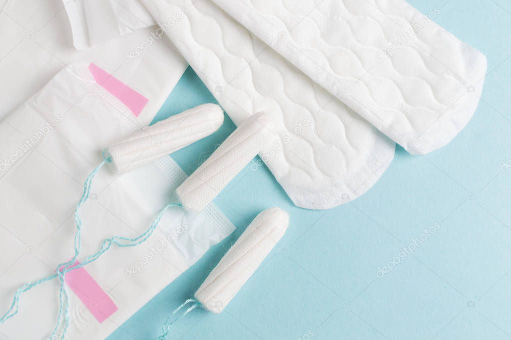 Menstrual tampons and pads on a blue background. Menstruation time. Hygiene and protection