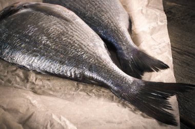 Taze dorado ahşap masanın üzerine parşömen kağıt üzerinde balık. kopya alanı