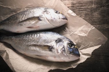 Taze dorado ahşap masanın üzerine parşömen kağıt üzerinde balık. kopya alanı