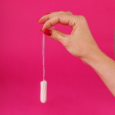 Adet tampon pembe bir arka plan üzerinde tutan kadın. Adet zamanı. Hijyen ve koruma