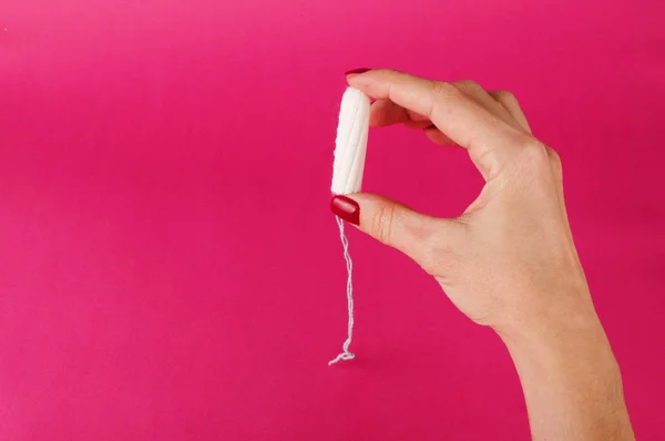 Mulher segurando tampão menstrual em um fundo rosa. Hora da menstruação. Higiene e protecção — Fotografia de Stock