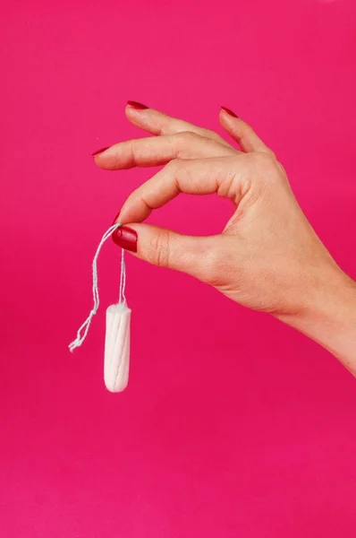 Mujer sosteniendo tampón menstrual sobre un fondo rosa. Tiempo de menstruación. Higiene y protección — Foto de Stock